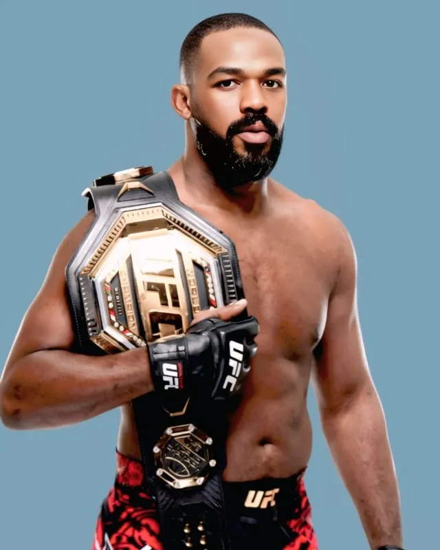 A muscular, bare-chested male mixed martial artist holding a UFC championship belt, with a neutral background.